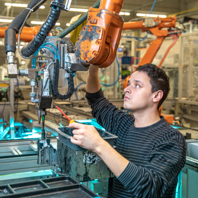 engineer performs maintenance of industrial robot in a factory