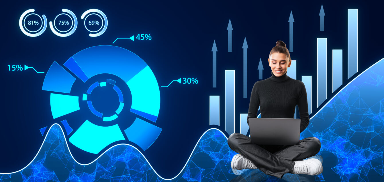 Happy young woman with laptop and creative digital business pie chart on dark background. Glowing stock market analysis and big business data analysis.